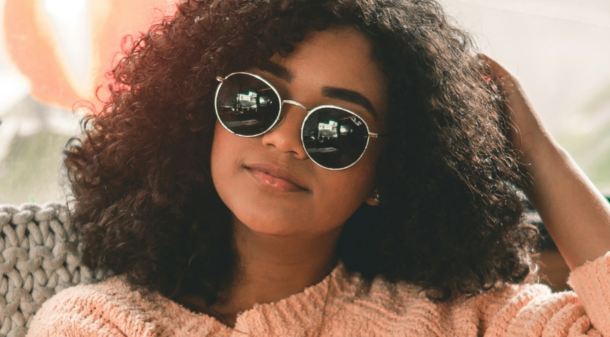 woman with curly hear wearing circular glasses