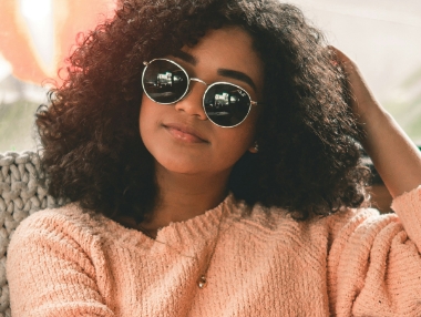 woman with curly hear wearing circular glasses